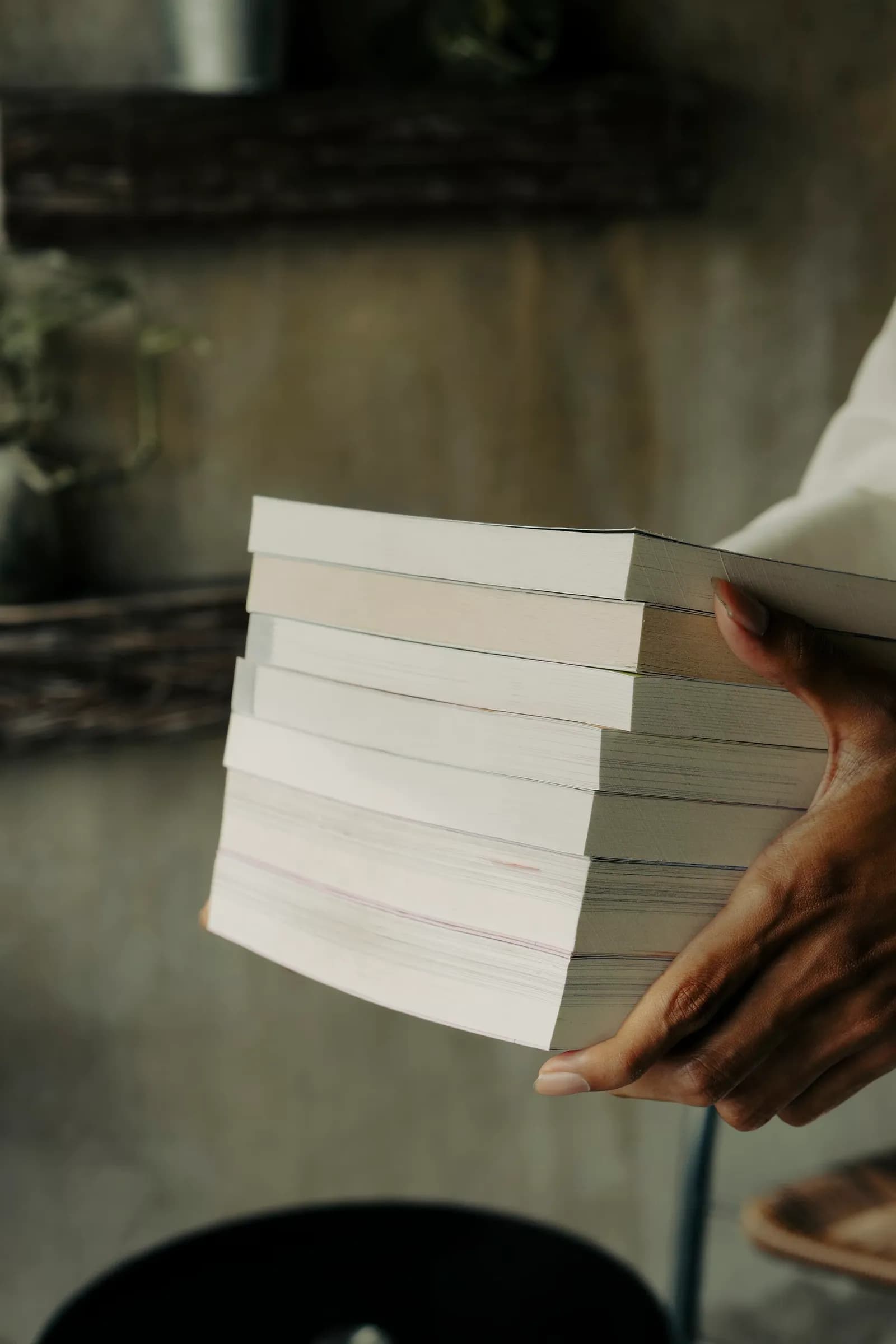 A person holding a stack of books in their hands