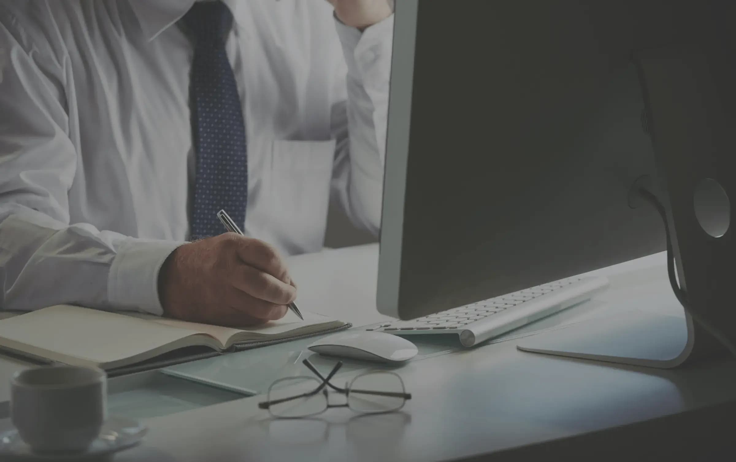 Fund administrator taking notes beside a computer
